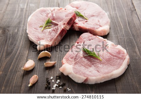 Raw pork chop with garlic and pepper on wooden background.