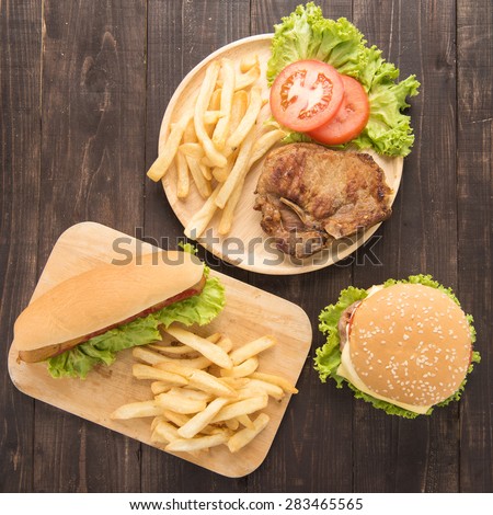 Hot dogs, hamburgers and grilled pork chop steak on the wooden background