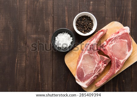 Fresh pork chops with pepper and salt on wooden background.