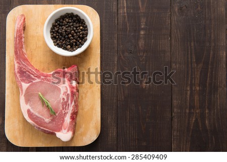 Fresh pork chops and pepper on wooden background.