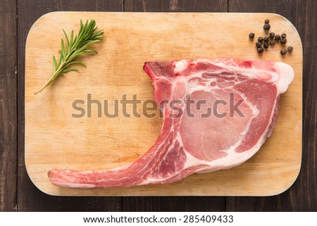 Fresh pork chops and pepper on wooden background.