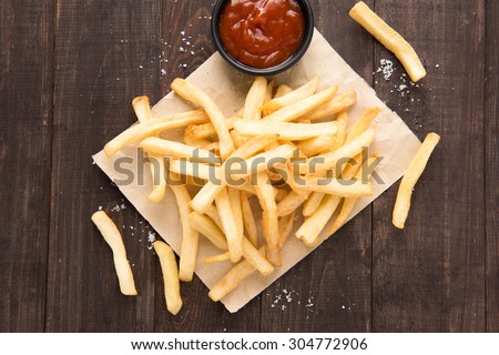 French fries with ketchup on wooden background.