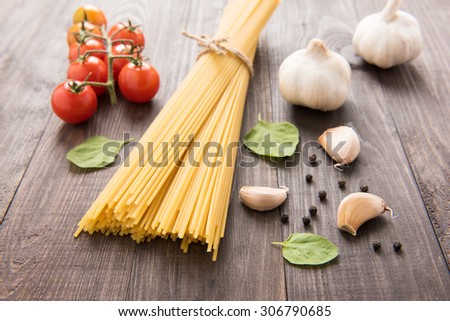 Pasta and tomatoes with herbs on vintage wooden table.