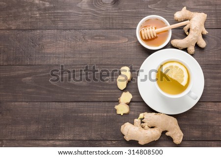 Cup of ginger tea with lemon and honey on wooden background.