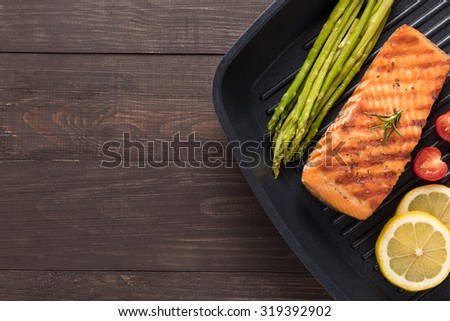 Grilled salmon cooked BBQ on a pan on wooden background.