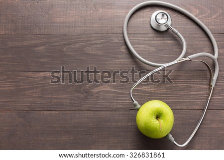 Concept for healthcare, Stethoscope and green apple on wooden background.