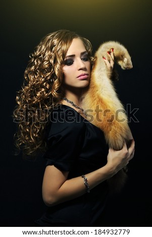 Elegance woman holding a fox fur on a black background