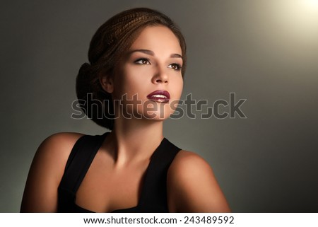Young woman with beautiful makeup and retro hairstyle on gray background