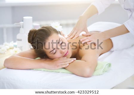 Beautiful young woman relaxing in the spa salon on light background