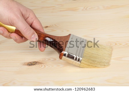 hand with paintbrush on wood