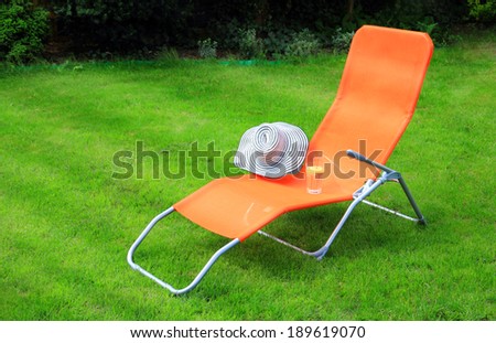 orange lounge sunbed standing on green grass in a private green garden
