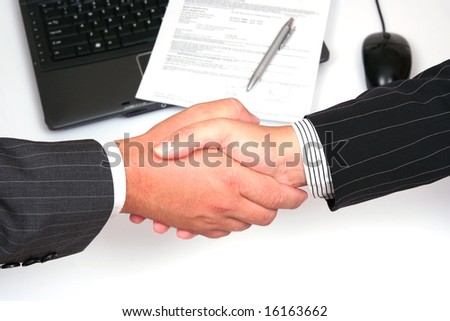 man and woman shaking hands in front of laptop and signed contract