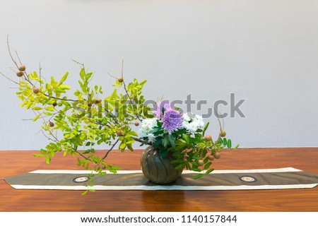 Ikebana, colorful flower in vase on wooden plate.Japanese style ,Ikebana is the Japanese art of flower arrangement. It is more than simply putting flowers in a container .Decorative item concept
