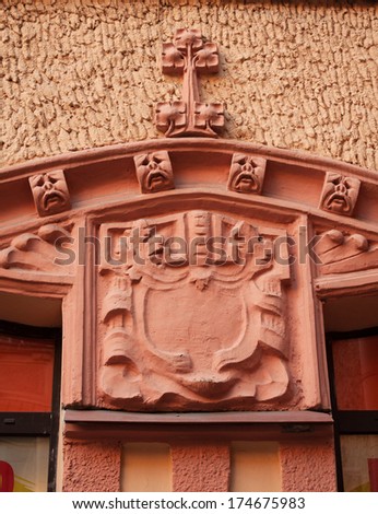 Decorative element facade of the house, coat of arms and crying pig faces