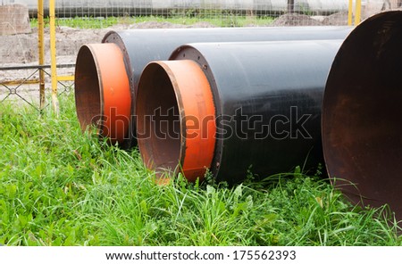 Black and orange water pipes lying on green grass