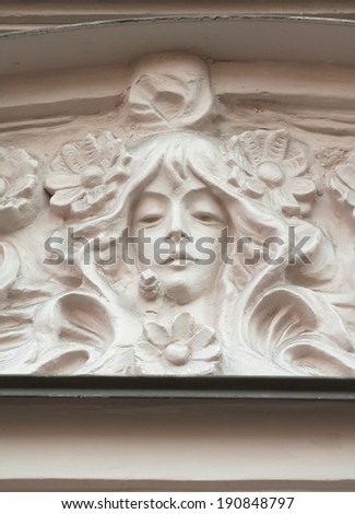 Detail of pediment building, decorated with sculpture female head in Art Nouveau style