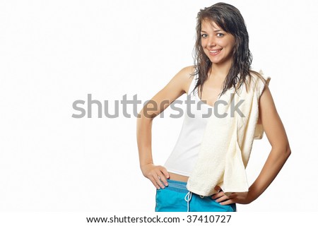 Young pretty happy woman in white vest with wet hair with hands on waist and with towel on shoulder