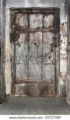 Old, dirty door from wooden boards on metal loops.