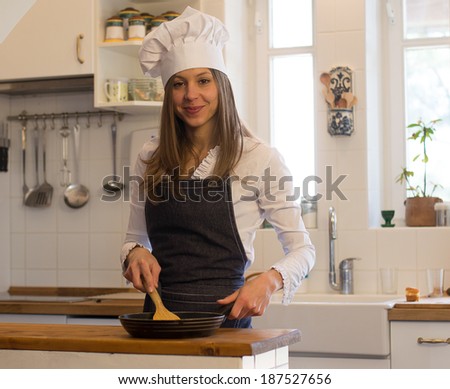 Woman standing by the stove in the kitchen, cooking and smelling the nice aromas from her meal in a pot