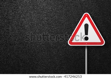 Road sign triangular shape with exclamation mark on a background of asphalt. The texture of the tarmac, top view.