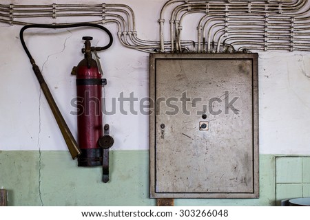 Old electrical cabinet and fire extinguisher hanging on the wall. old construction office.