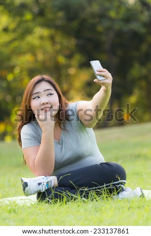 Beautiful obese woman sitting on the grass, and taking her self.