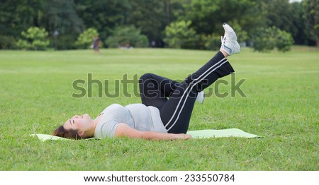 Obese woman  bicycle kick exercise on the grass.