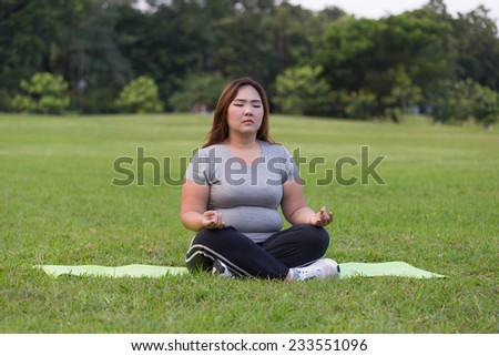 Obese woman yoga on the grass.