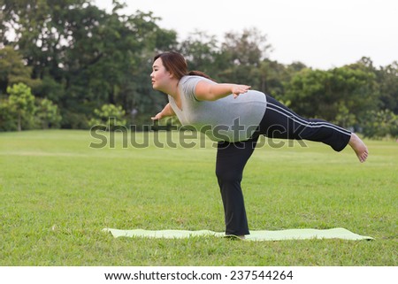 Obese woman yoga on the grass.