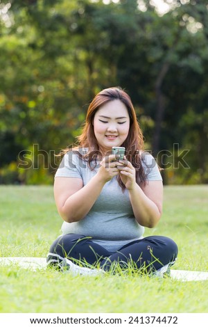 Obese woman sitting on grass and taking selfie