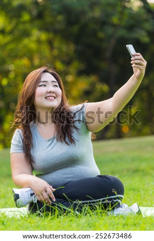 Beautiful obese woman sitting on the grass, and taking her self.