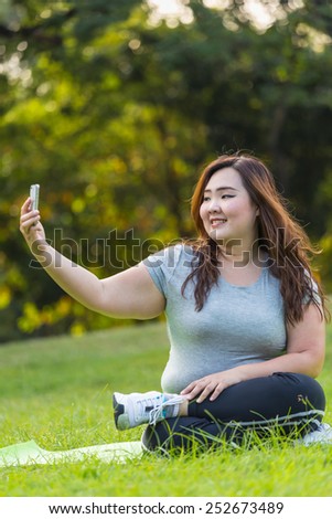 beautiful obese women sitting on grass and taking selfie
