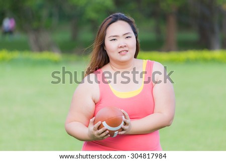 Beautiful fat woman playing american football in the park.