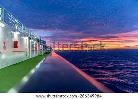Side of a cruise ship, with moving water and a beautiful sunrise