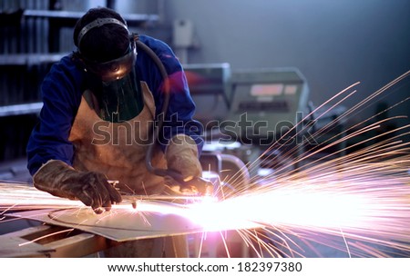 worker inside factory cut metal using blowtorch
