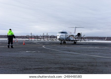 NIZHNY NOVGOROD. RUSSIA. January 26, 2015. STRIGINO AIRPORT. The employee of the MANN airport specifies to the pilot of the Bombardier CRJ 100 plane of RusLine airline a parking lot
