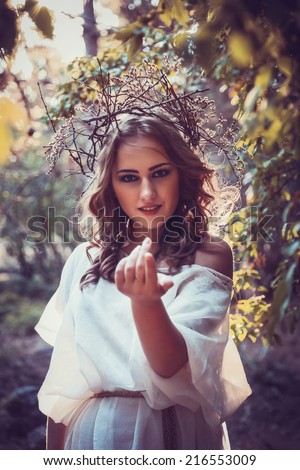 portrait of beautiful girl with magic eyes in wreath and dress in the forest outdoor. Bright witch, druid, shaman. book cover