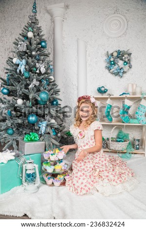 pretty little girl near the new year tree. beautiful girl in a wreath and dress near Christmas tree waiting for holiday