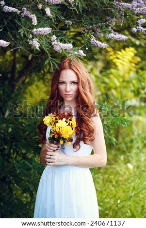 Beautiful red hair bride with bright bouquet of daisies outdoors, on forest. Toning and softness