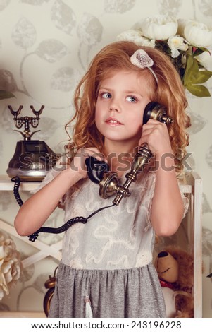 Cute little child girl with spring flowers, happy baby girl with basket of flowers. retro phone, a rack with flowers and cute attributes