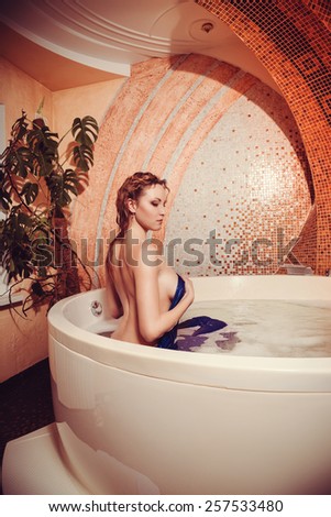 Young woman with red hair take bubble bath with candle.