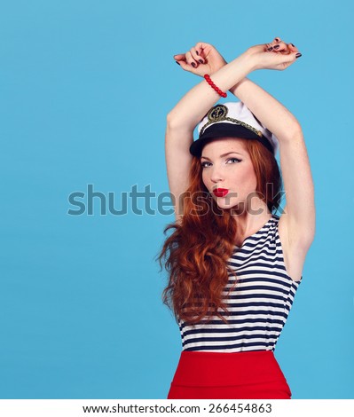 Beautiful red-haired girl in a sailor suit. Pin-up style, blue background with copy space