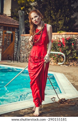 Young sexy woman floating on swimming pool in red dress. Beautiful rich lady who was strangled and thrown off into the water, but she is alive