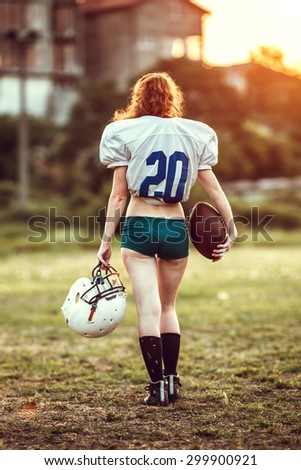 American football woman player in action on the stadium. back view