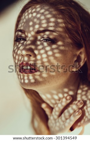 Portrait of a charming young woman outdoor. Light and shadow. interesting portrait of young girl\'s face covered with unusual shadow