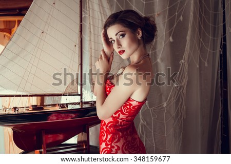 Beautiful sexy woman in restaurant cafe girl rich stylish lady resting at retro villa hotel with hairstyle makeup jewelry in evening dress. Interior and street photography