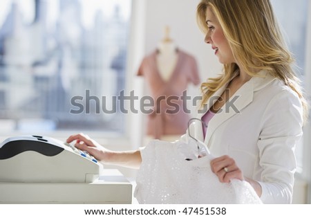 female store employee selling clothing at register