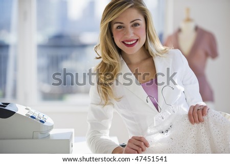 female store employee holding up clothing behind register