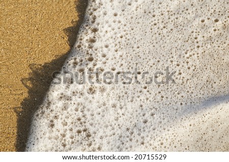 wave and white foam moving over sand