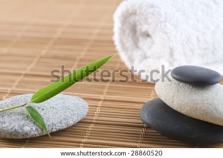 bamboo leaf and stones on a bamboo mat with towel in the background